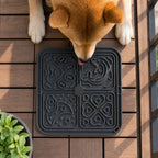 Dog licking a black lick mat on a wooden deck
